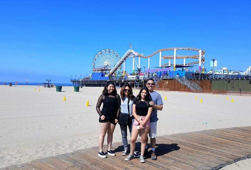 family of four standing near amusement park in los angeles beaches
