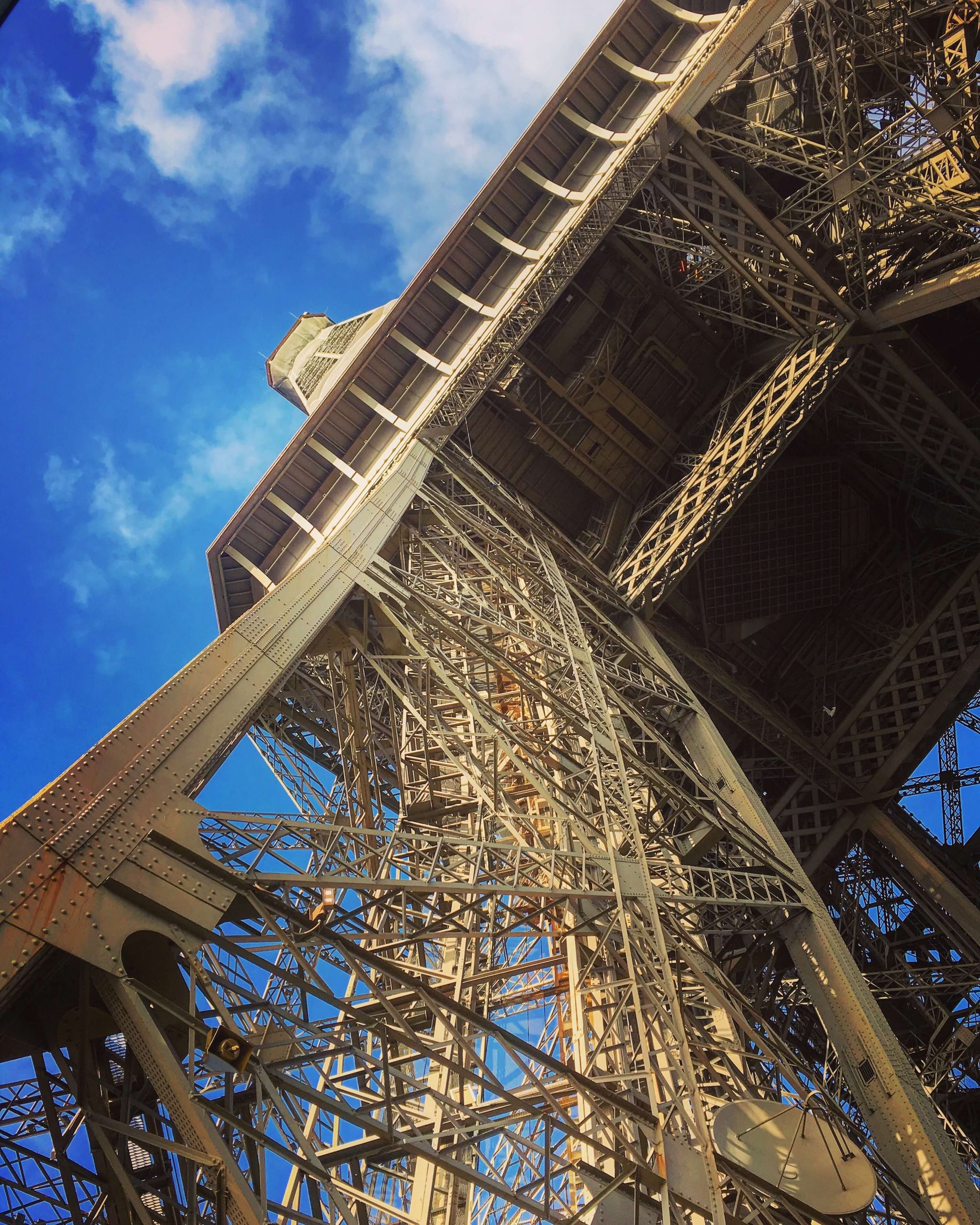 Looking up to the top of the Eiffel Tower with bright blue sky