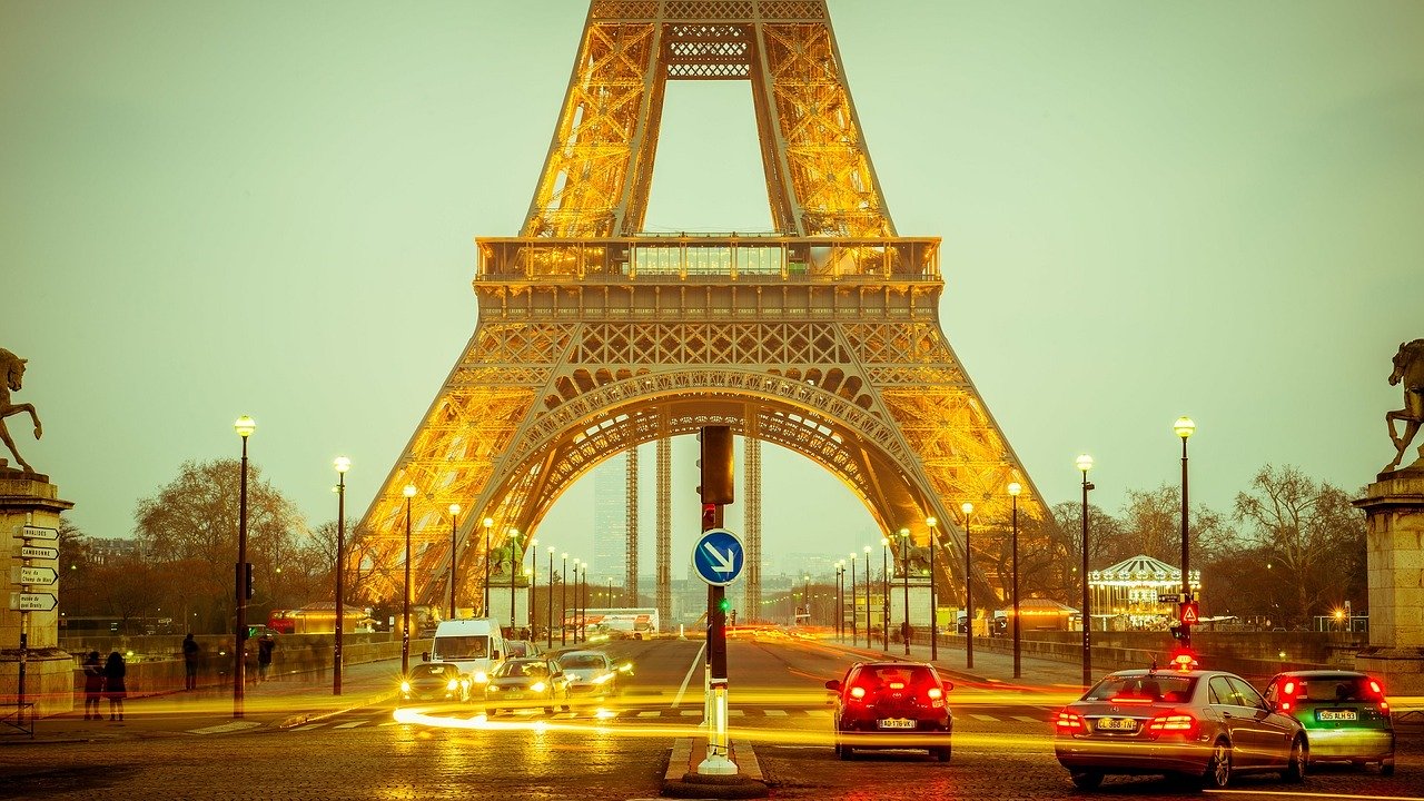 Eiffel Tower at night with cars driving near the base