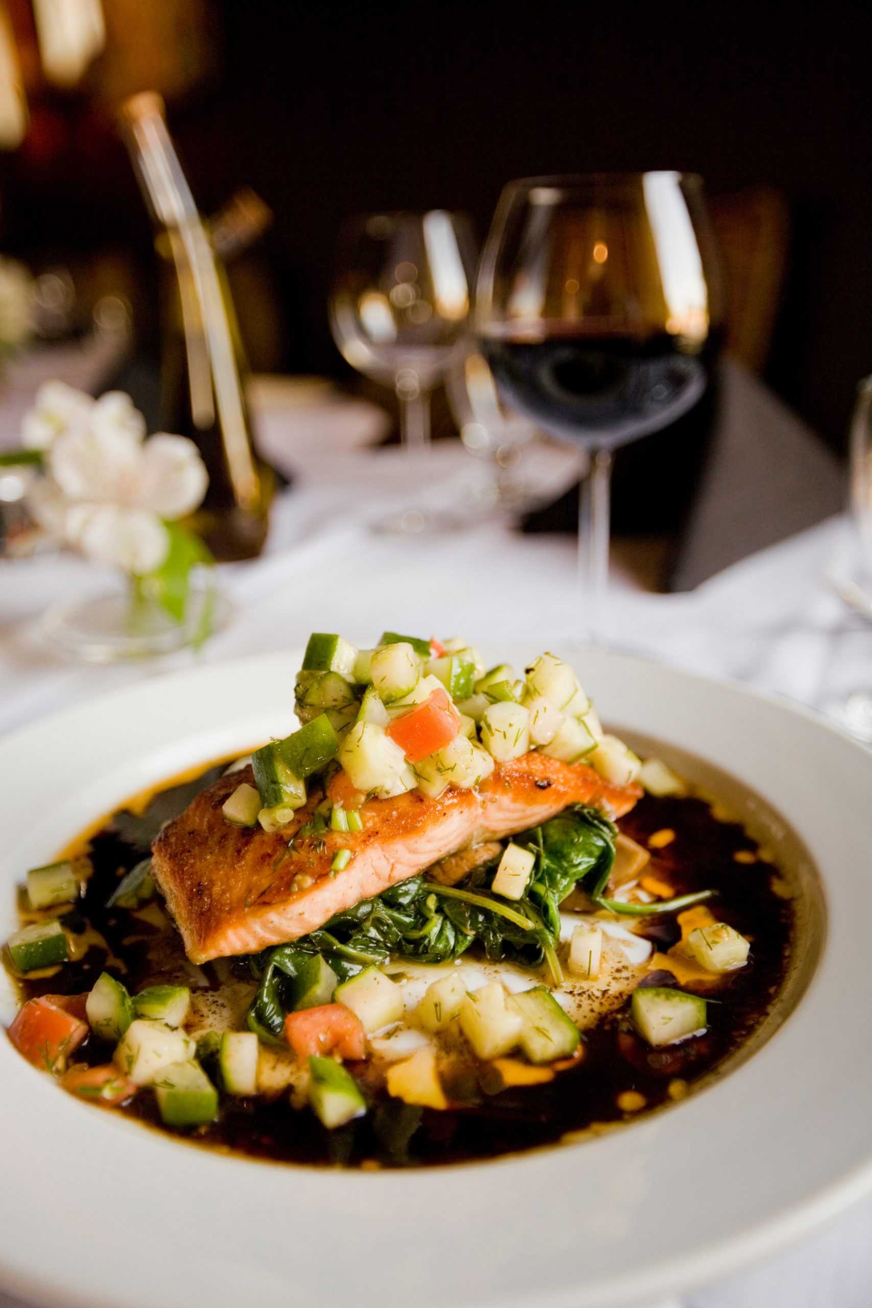 Salmon and vegetables on a plate and glass of red wine