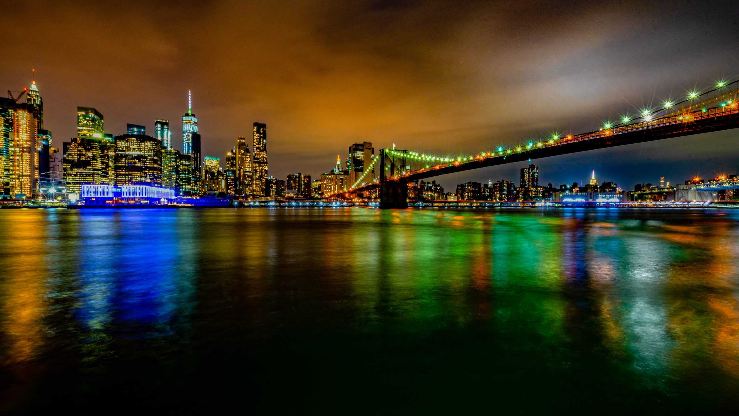 Multi-colored lights at night with buildings and a bridge