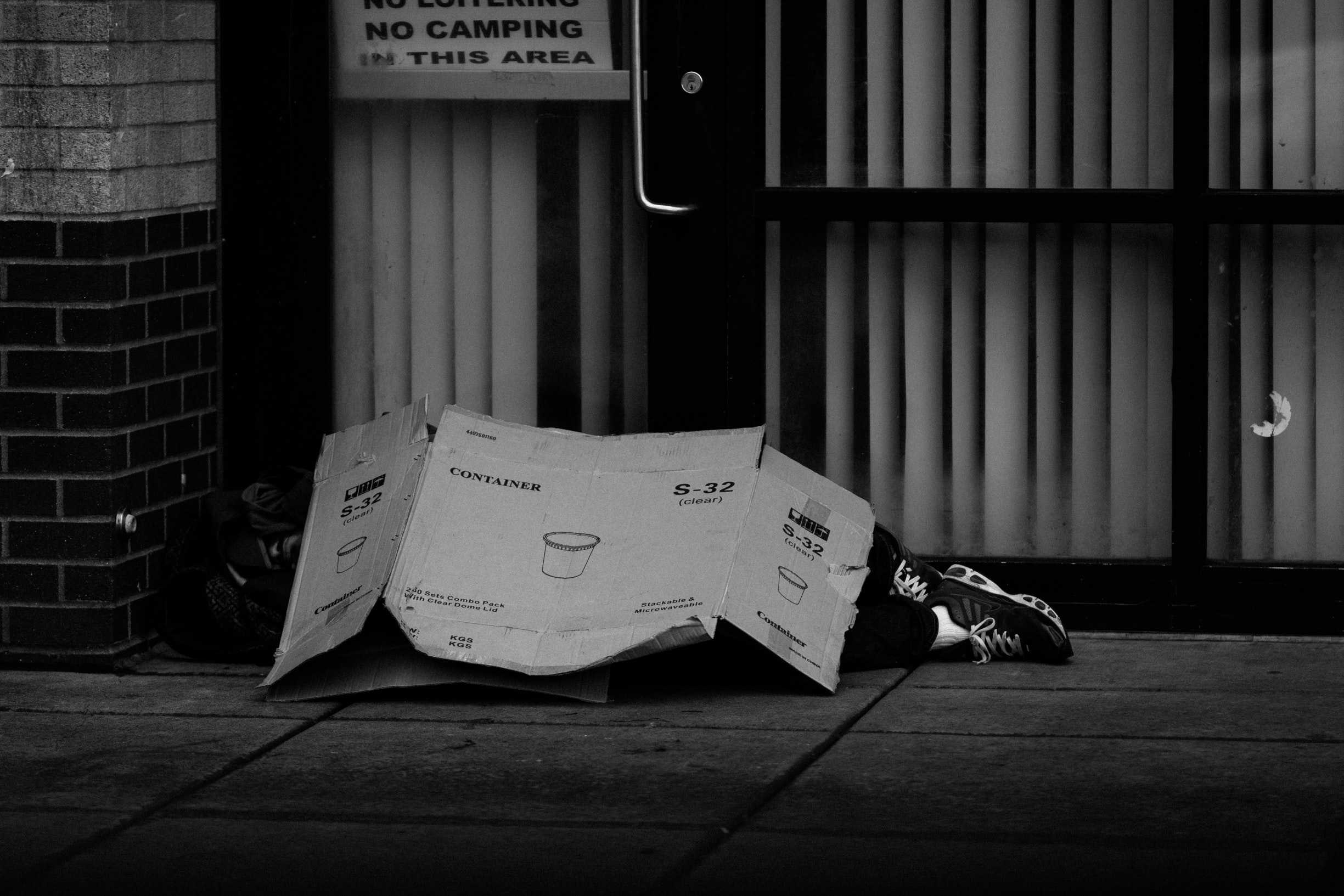 man sleeping under cardboard