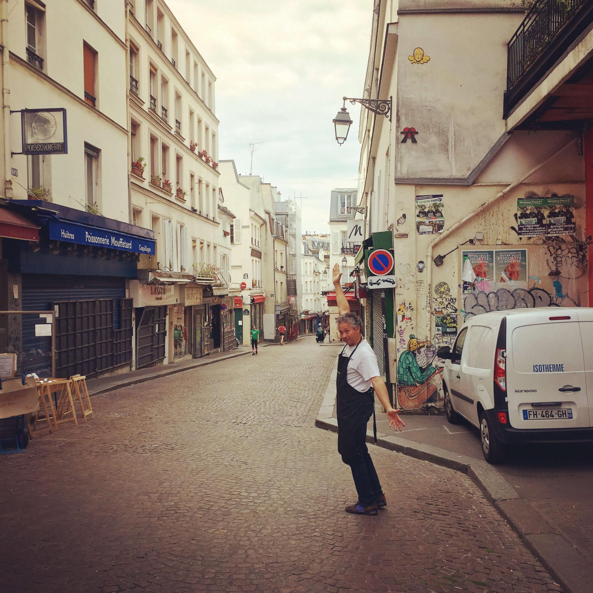 Smiling man with arms in the air on rue Mouffetard in Paris