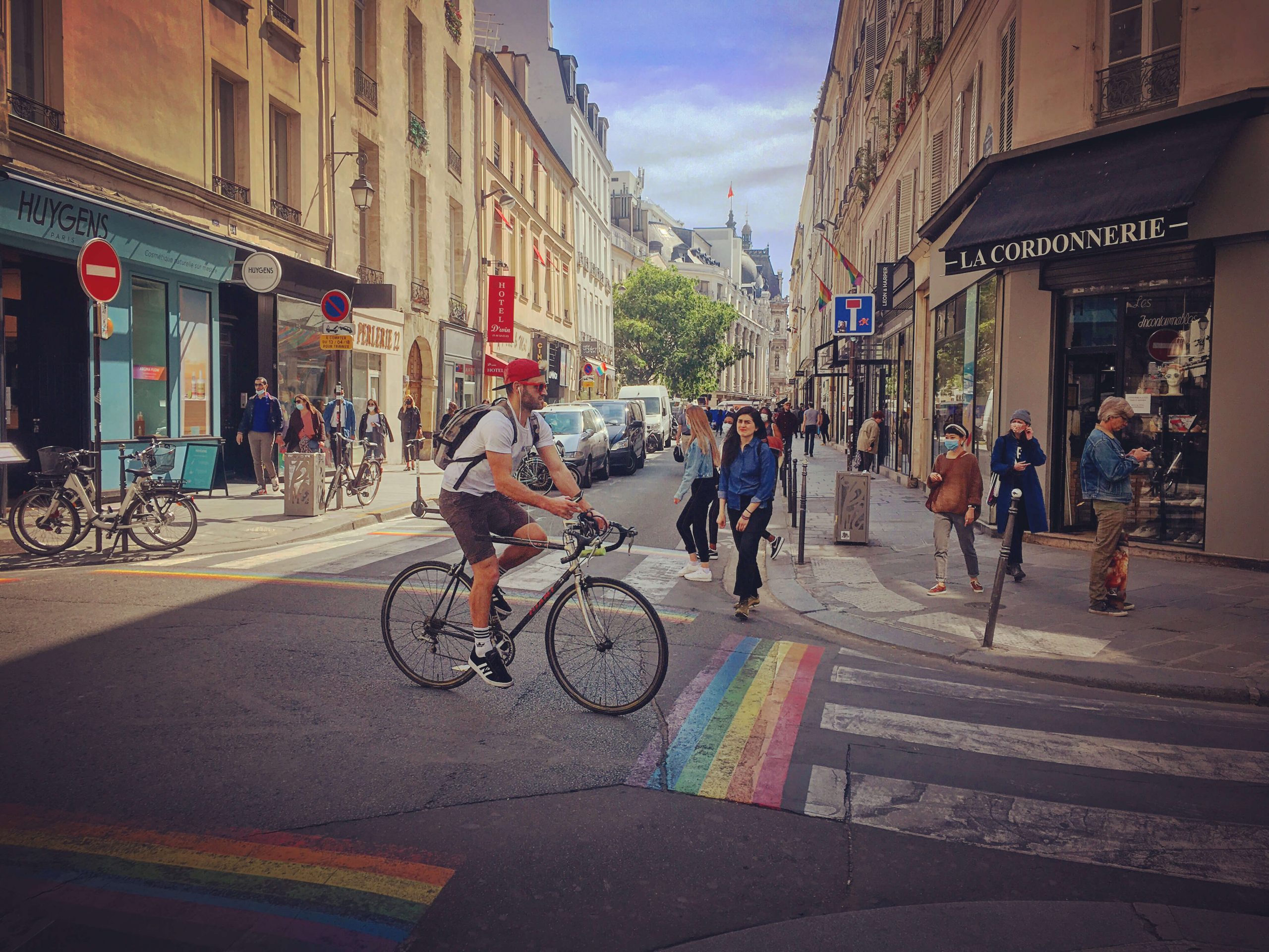 Man riding a bicycle through intersection with rainbow crosswalks