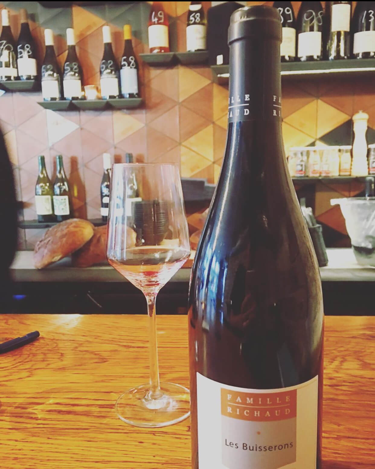 Bottle of wine and glass of wine on a wooden bar counter