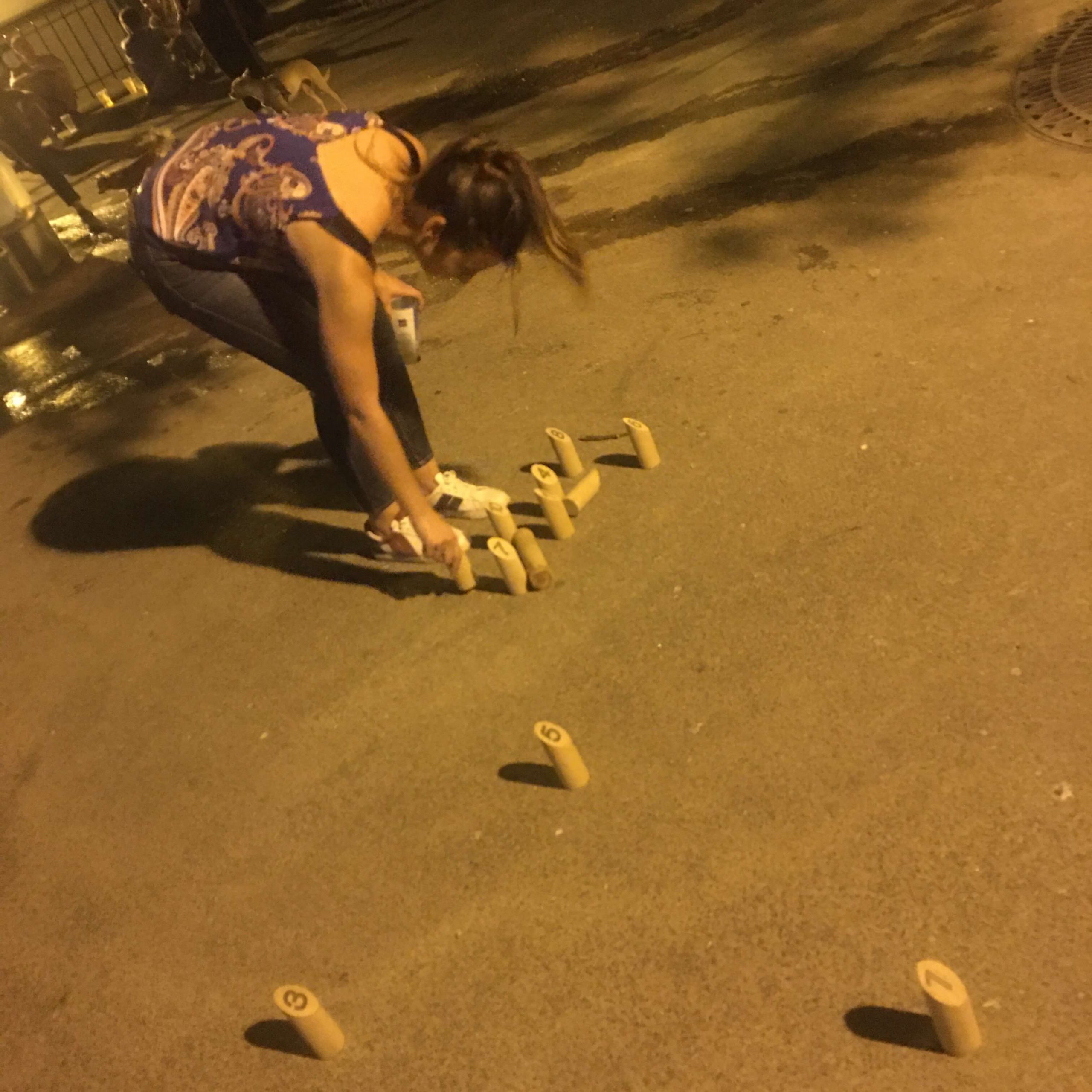 A woman playing Mölkky bending over to stand up wooden playing pins