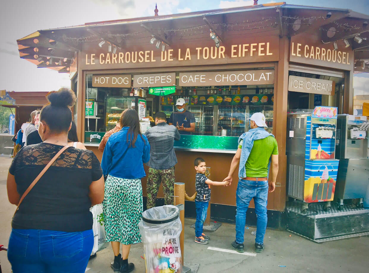 People stand in line at a kiosk to order hot dogs, crepes, coffee, chocolate