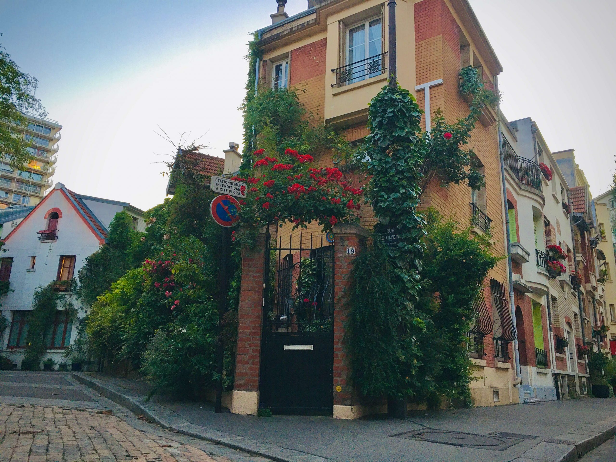 House on a corner with many flowers and vines climbing up the front