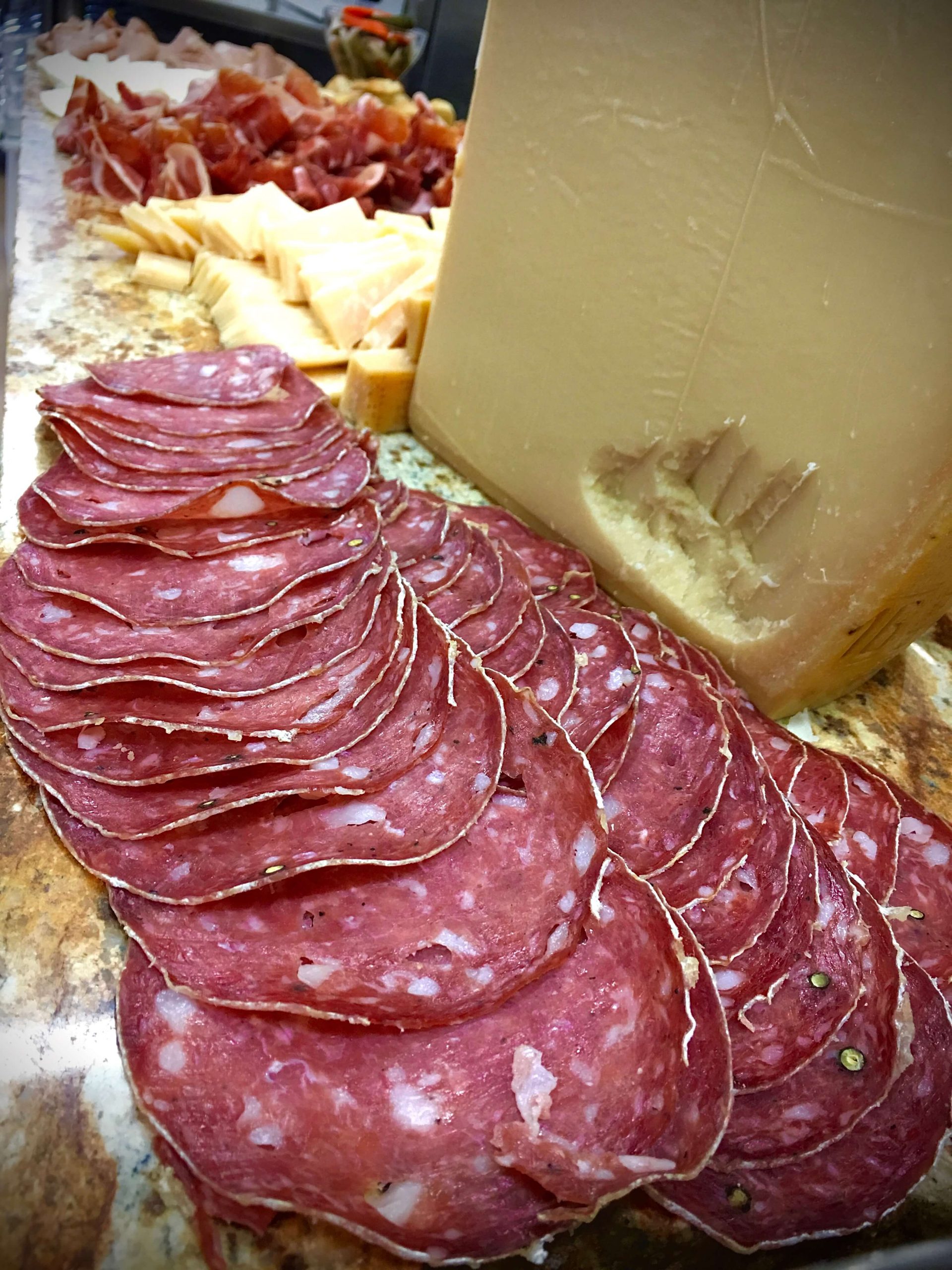 Sliced salami and a hunk of pareggiano reggiano cheese