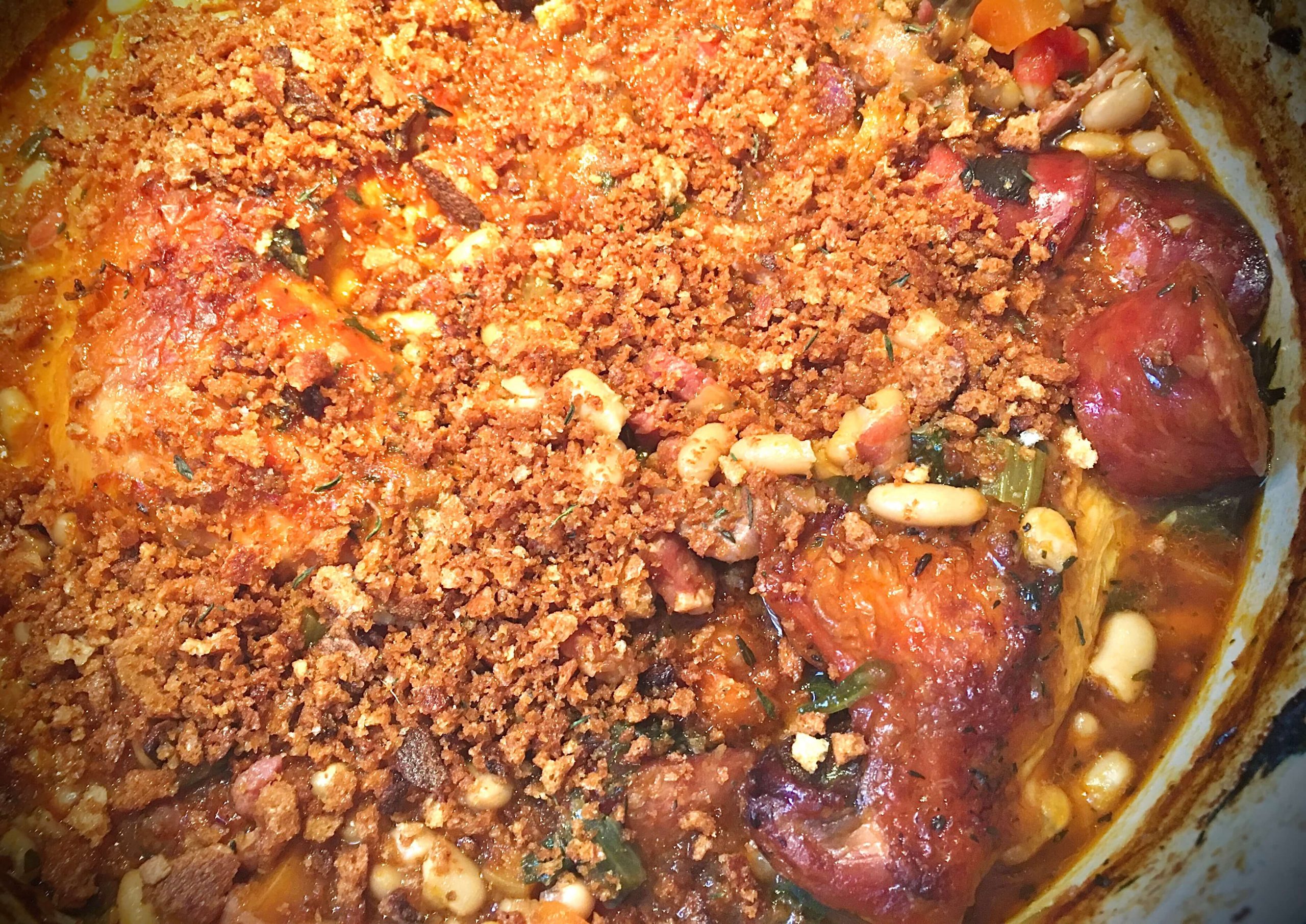 A pot of Cassoulet topped with crunchy breadcrumbs