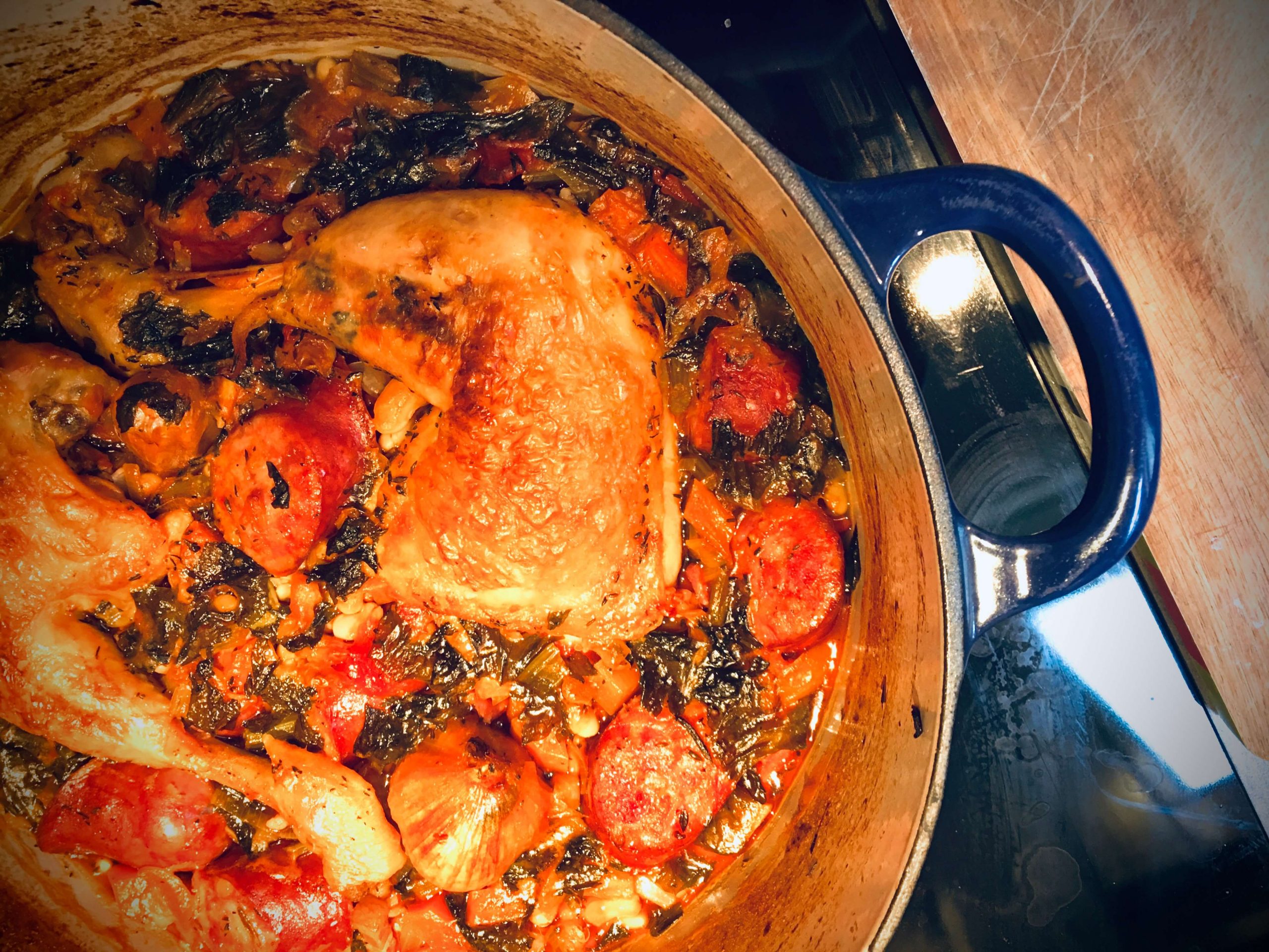 A blue dutch oven with Cassoulet on the stove