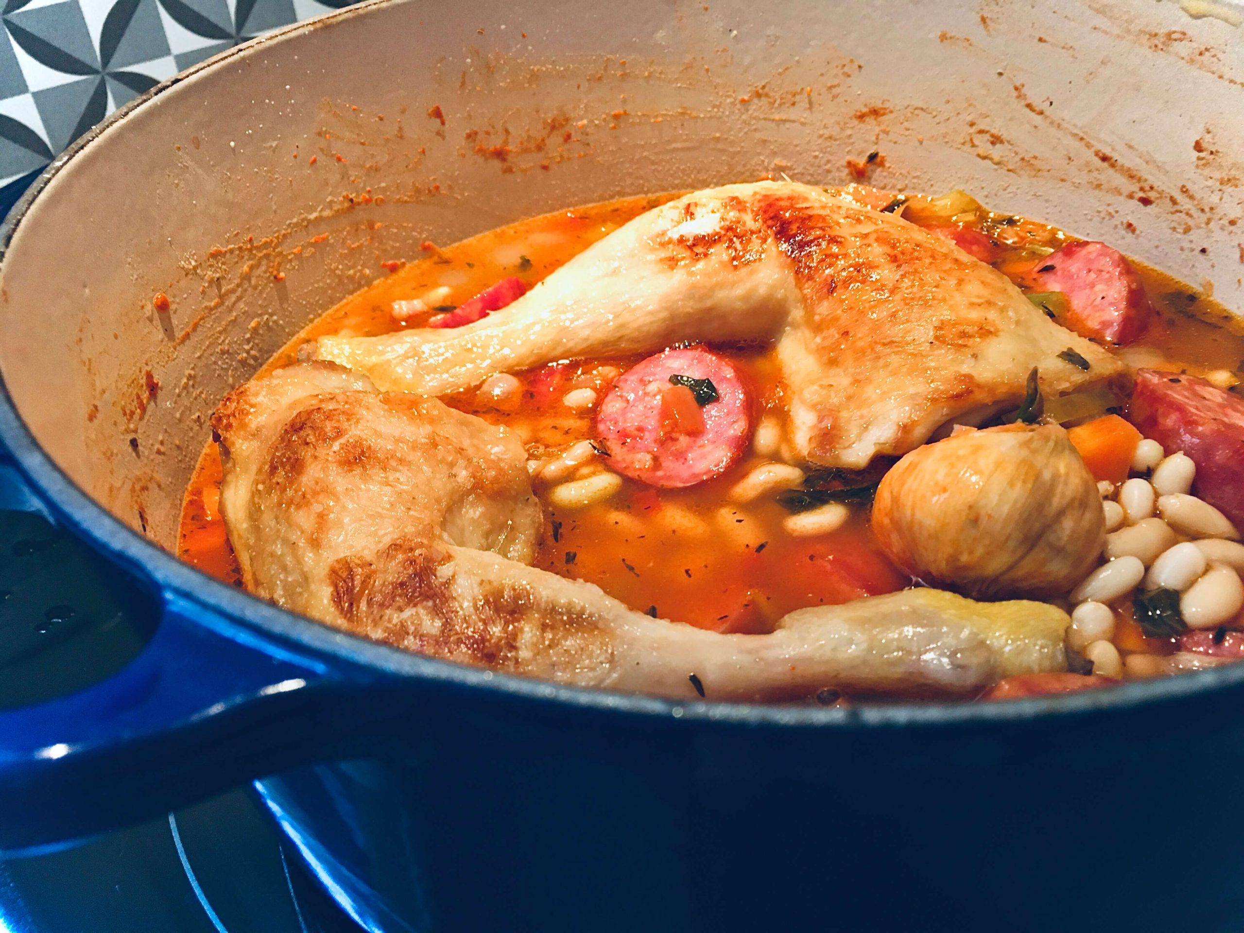 A blue pot with beans, sausage and chicken stewing