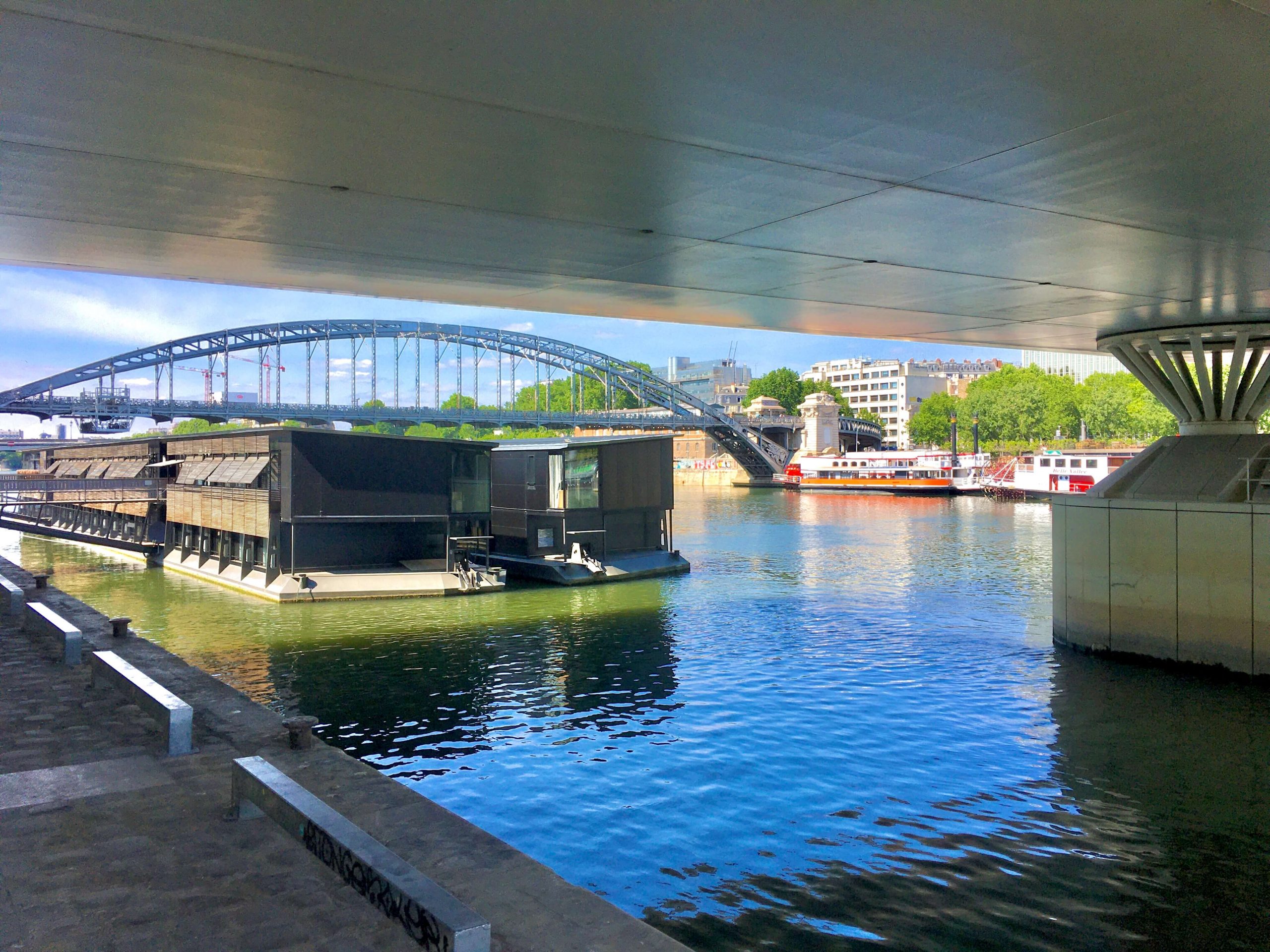 A boat that is also a hotel is floating under a bridge in Paris