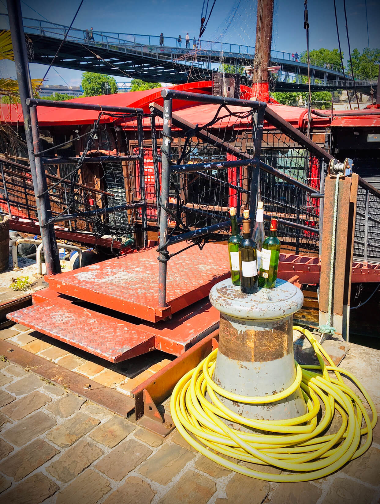 Four empty wine bottles on a concrete pillar next to a boat ramp