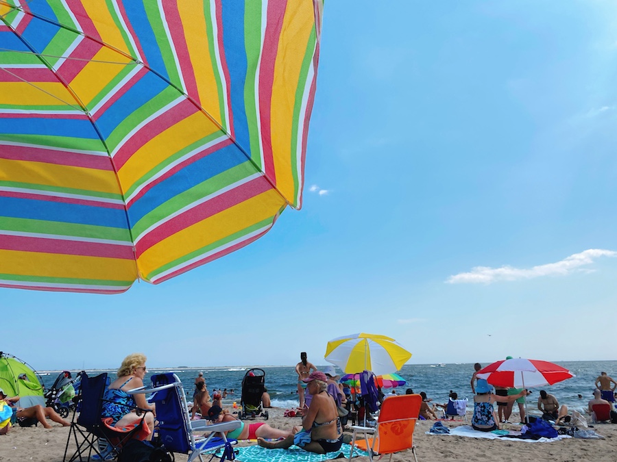 Beach umbrella at Brighton Beach with locals and visitors in summer