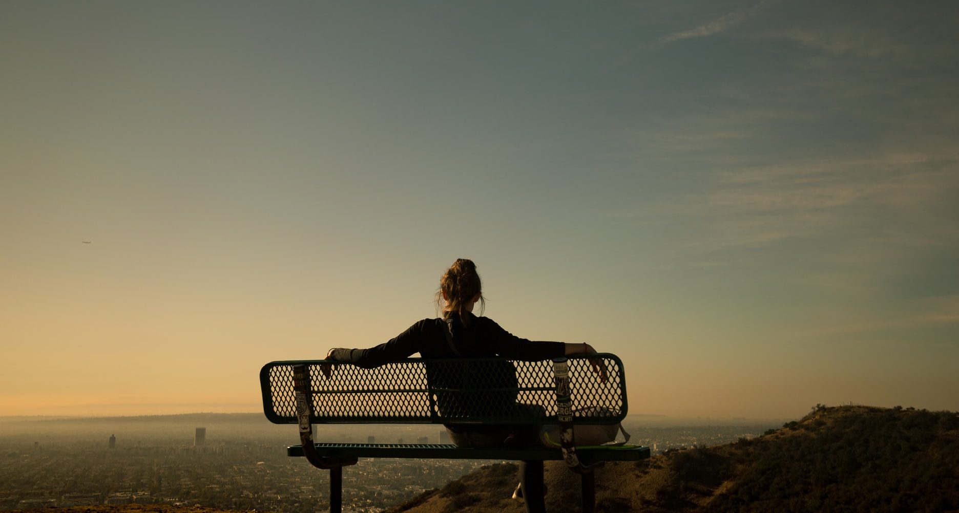 woman sitting on a bench at Runyon Canyon Park at sunset