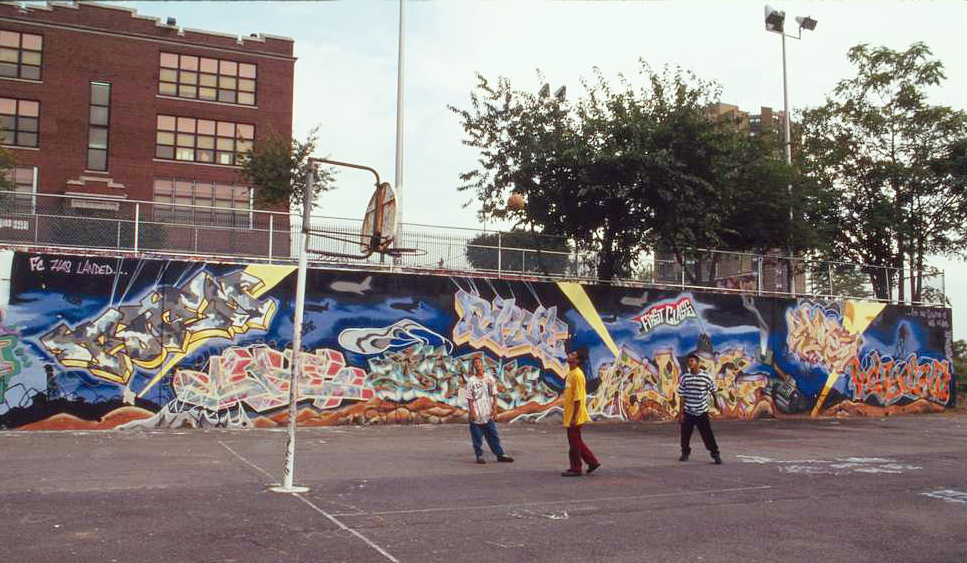 boys playing basketball by a graffiti-covered wall in the bronx