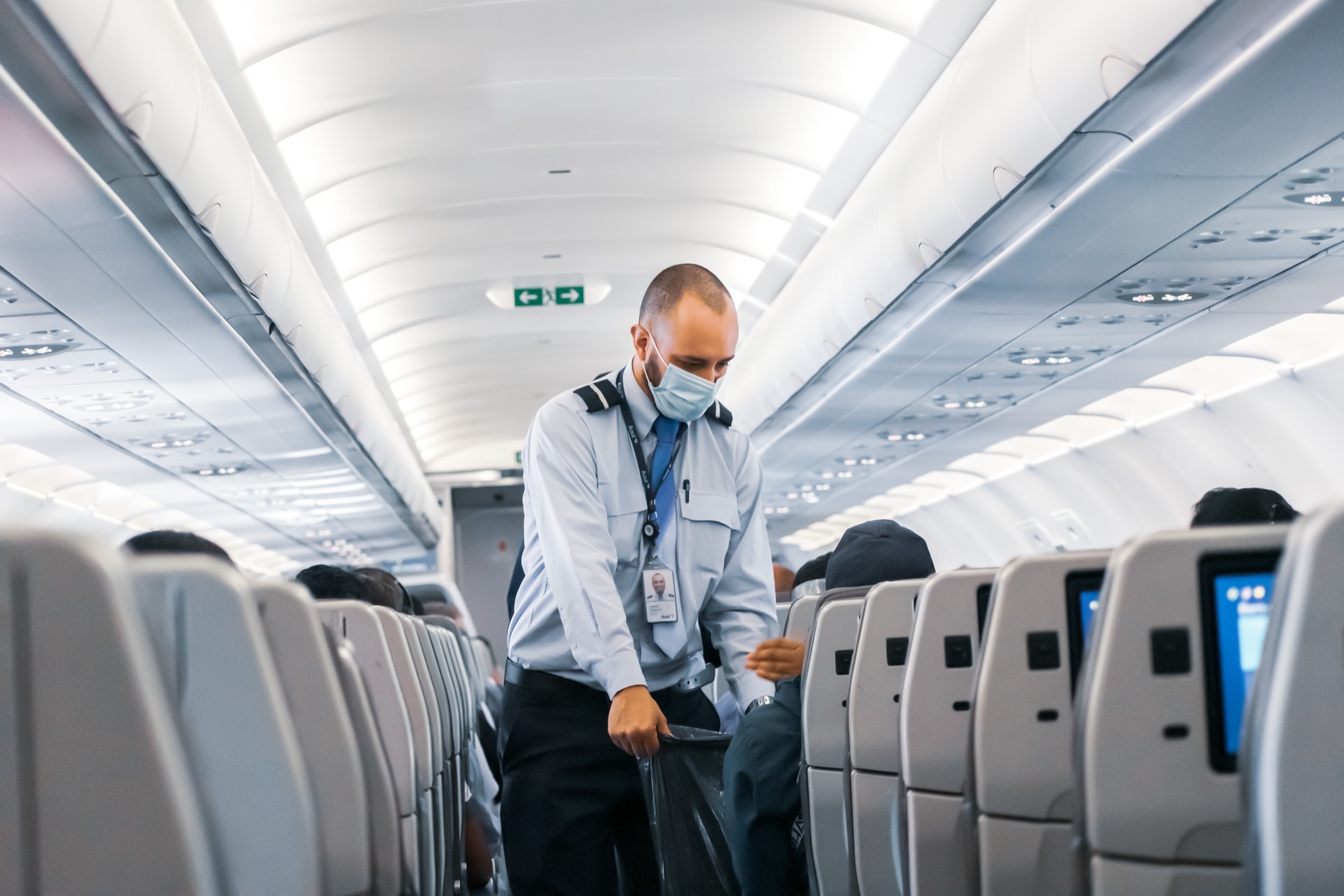 Flight attendant collecting trash during COVID