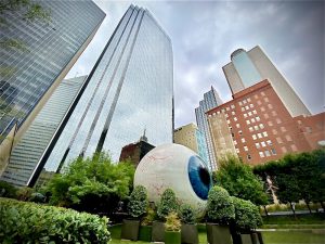 Giant Eyeball in Dallas surrounded by greenery and skyscrapers