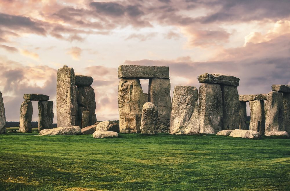 gray rock formation on green grass field under gray cloudy sky