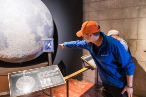 Tour Guide pointing at Moon Display in Griffith Observatory