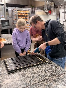 Father and daughter piping into tray
