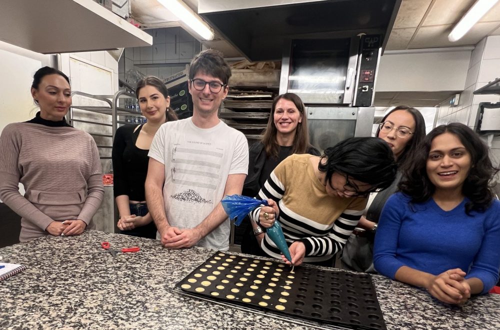 Group posing while guest pipes dough