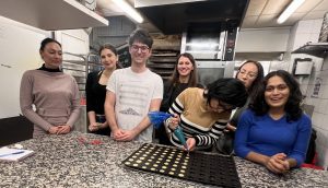 Group posing while guest pipes dough