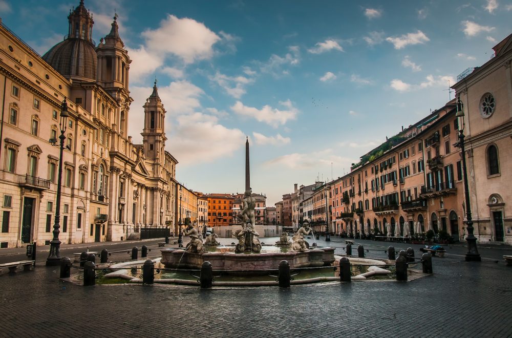 a canal with buildings along it with Piazza Navona in the background