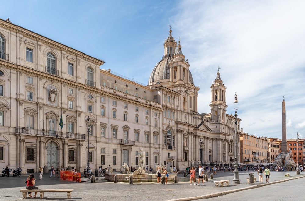a large building with a dome and many windows with Piazza Navona in the background