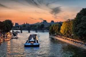 ferry full of people transiting through body of water at dusk