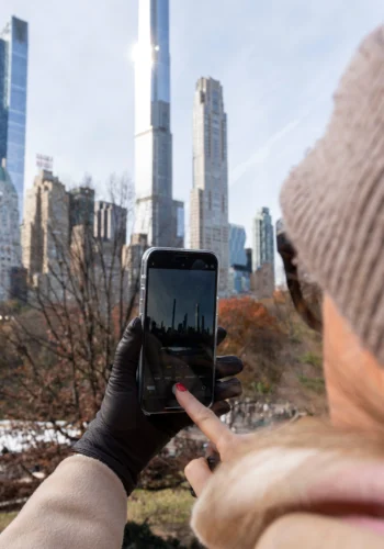 Woman taking a photo of NYC skyline from Central Park