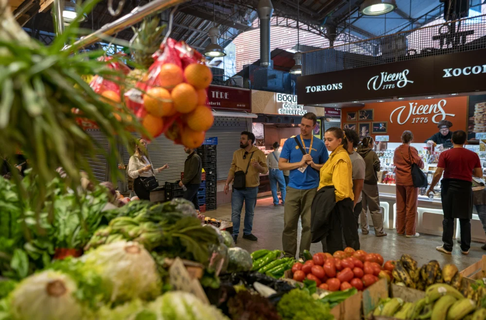 Guests and tour guide looking at fresh produce in market in Barcelona