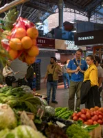 Guests and tour guide looking at fresh produce in market in Barcelona