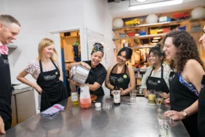 Host pouring drinks into jug with tour group during cooking class in Barcelona