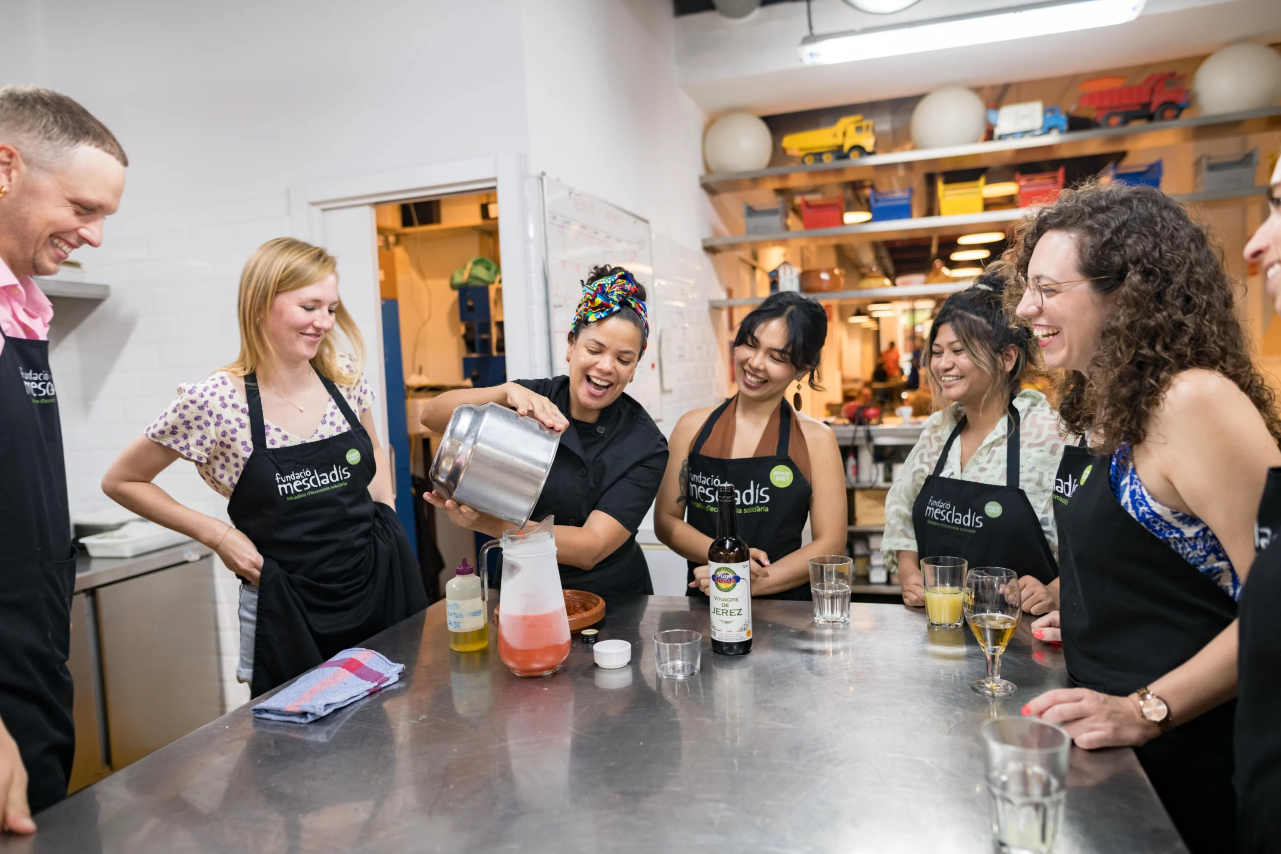 Host pouring drinks into jug with tour group during cooking class in Barcelona