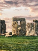 gray rock formation on green grass field under gray cloudy sky
