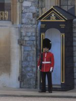 man in red and black uniform standing near gray concrete building during daytime