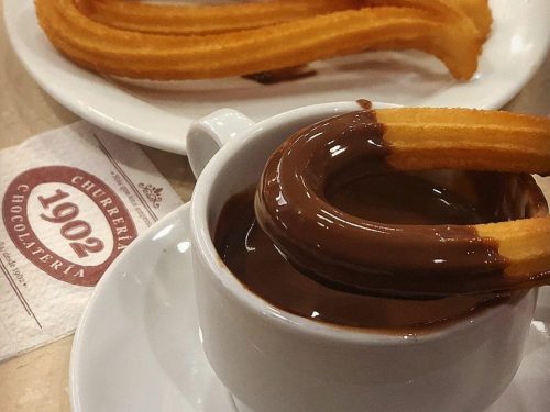 Churro dipped in chocolate at Churros and hot chocolate at Chocolatería 1902
