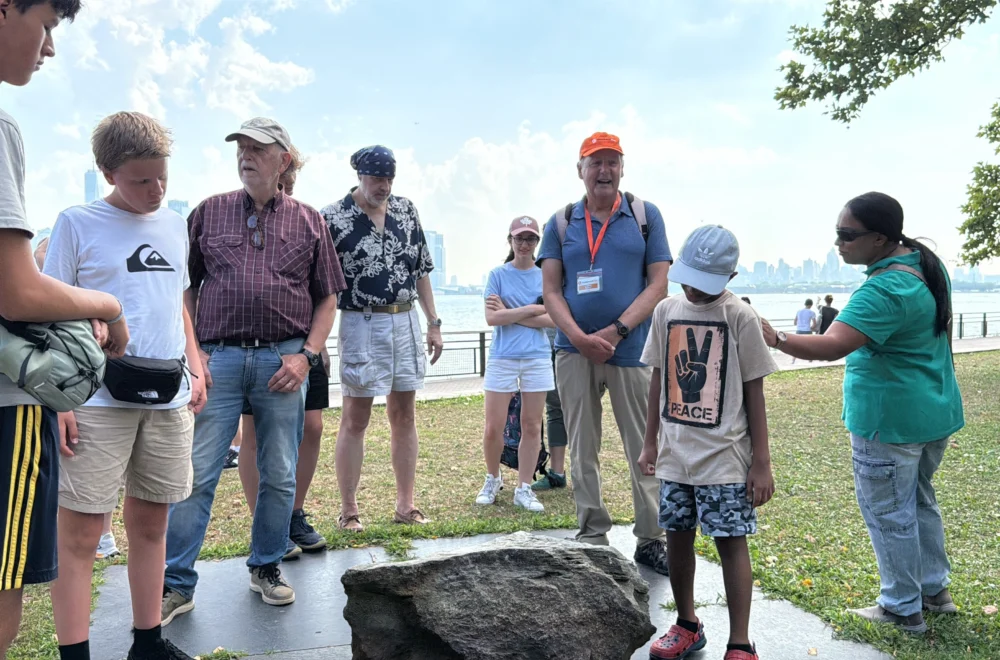 Tour guide showing historical artifact to group during Statue of Liberty and Ellis Island tour