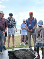 Tour guide showing historical artifact to group during Statue of Liberty and Ellis Island tour