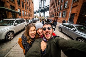 Friends taking selfie in Manhattan Bridge seen from Dumbo, Brooklyn, New York City