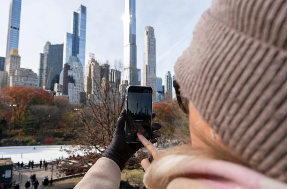 Woman taking a photo of NYC skyline from Central Park
