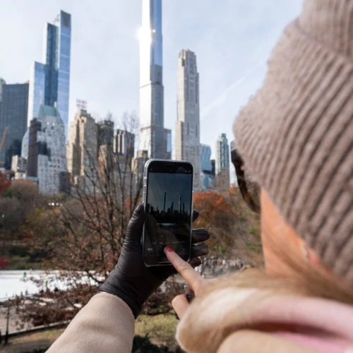 Woman taking a photo of NYC skyline from Central Park