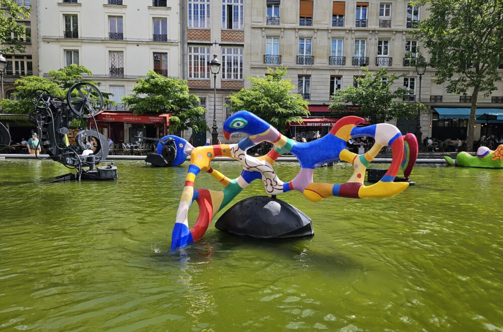 Whimsical modern fountain with bold sculptures in a public square in Le Marais, Paris.