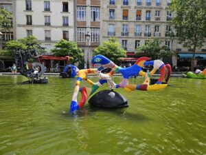 Whimsical modern fountain with bold sculptures in a public square in Le Marais, Paris.