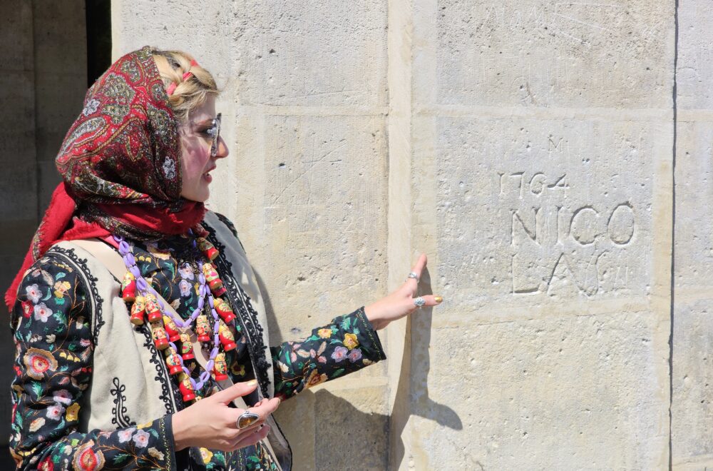 Tour guide pointing to a historic wall engraving in the Le Marais neighborhood.