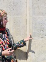 Tour guide pointing to a historic wall engraving in the Le Marais neighborhood.