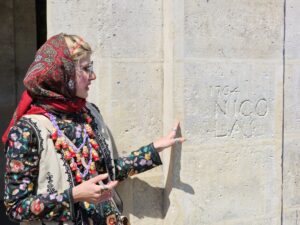 Tour guide pointing to a historic wall engraving in the Le Marais neighborhood.
