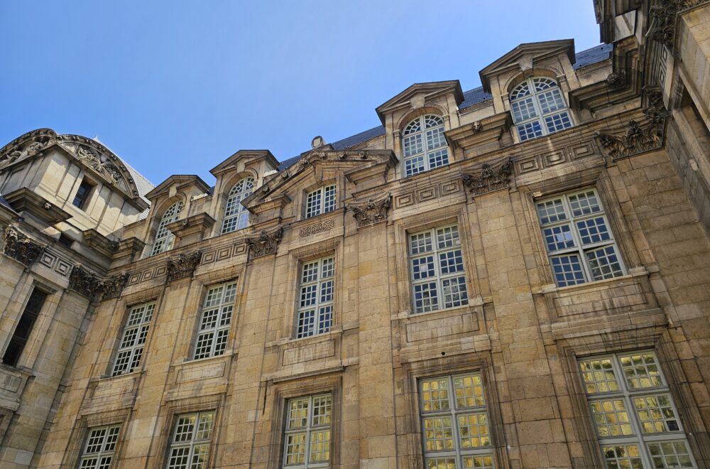Close-up of a grand Parisian building facade with classic French windows in Le Marais guided tour